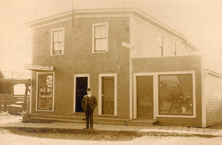 Man standing in front of Huntington Store Louisbourg, date unknown