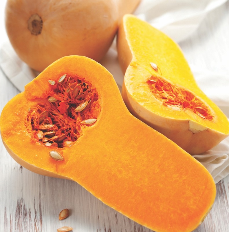 Butternut squash sliced open to show orange flesh and seeds.