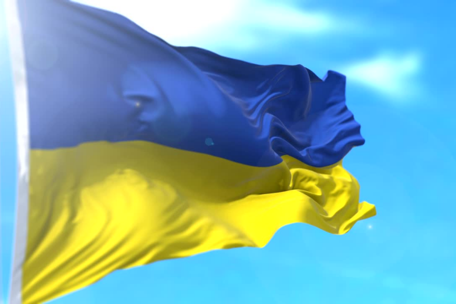 Ukrainian flag waving in wind, blue sky background.
