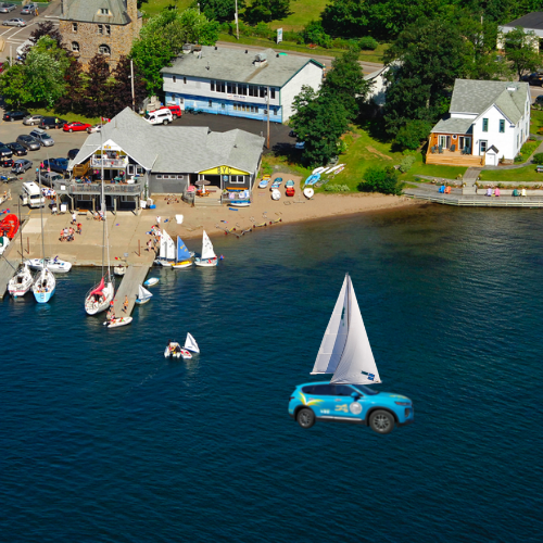 aerial photo showing bras d'or yacht club with blue victoria county outreach car superimposed.