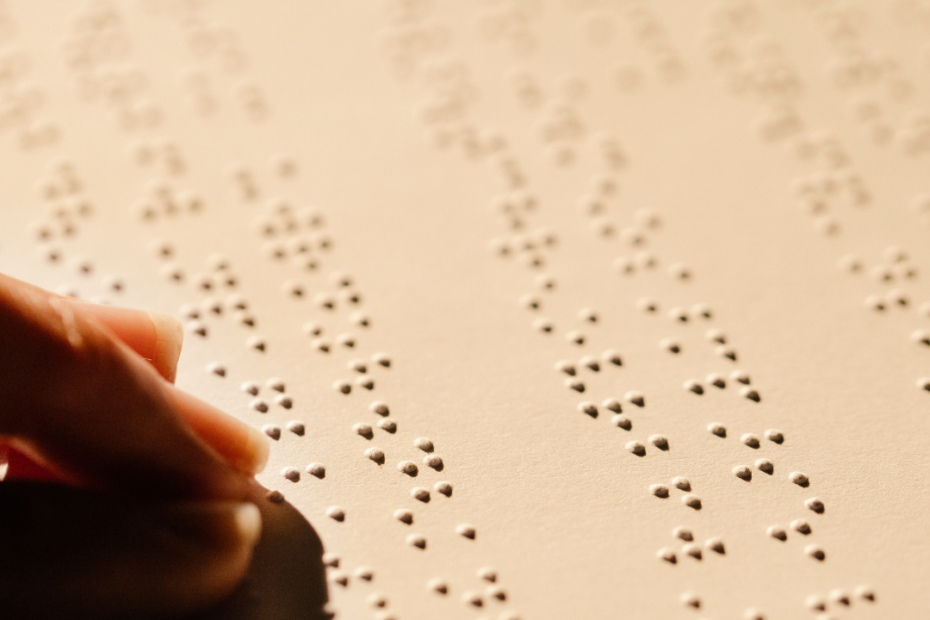 a person's hand reading a braille book