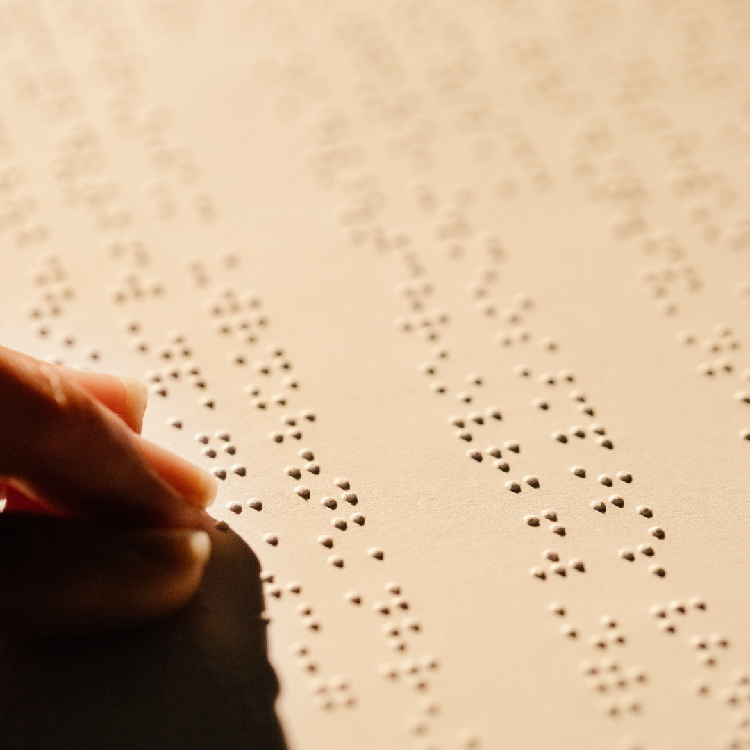 a person's hand reading a braille book