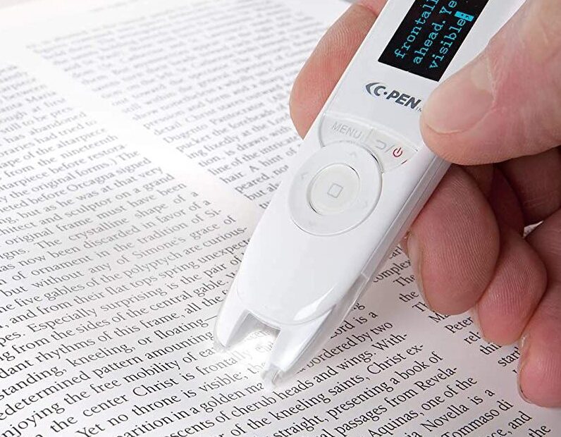 The C-Pen ReaderPen, a text-to-speech pen, is being used to scan and read text in a printed book.