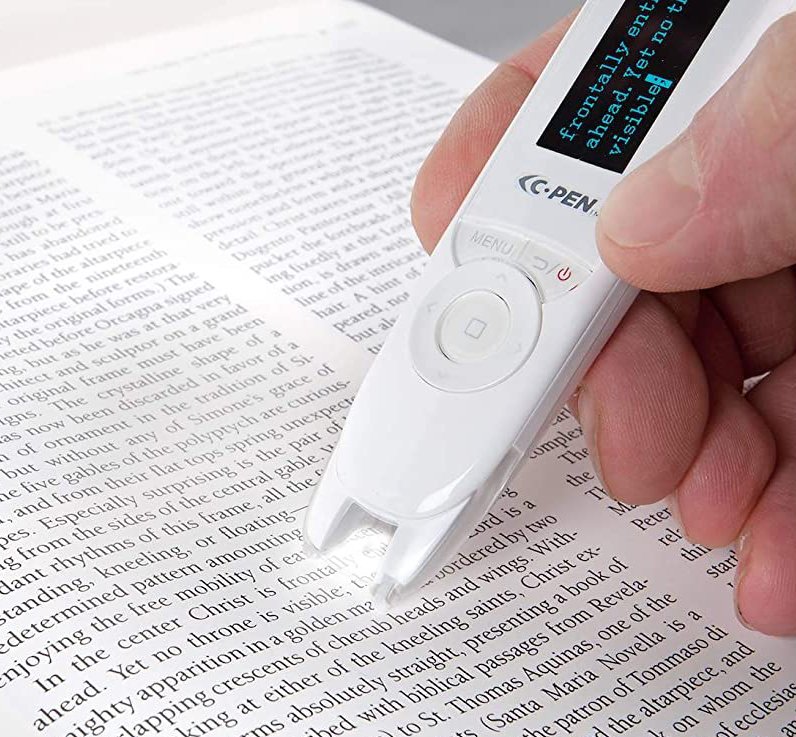 The C-Pen ReaderPen, a text-to-speech pen, is being used to scan and read text in a printed book.