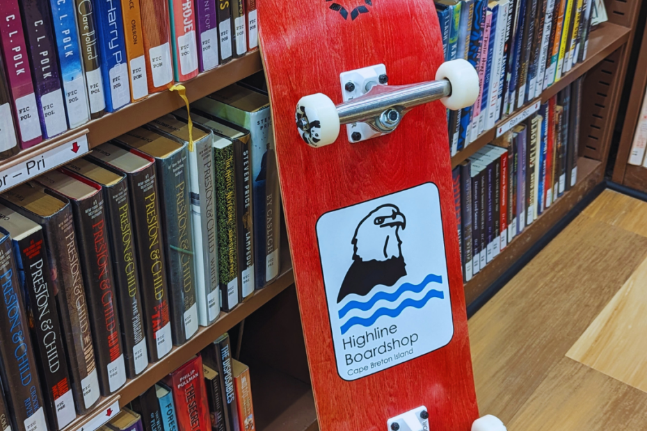 skateboard leaning against shelf of library books.